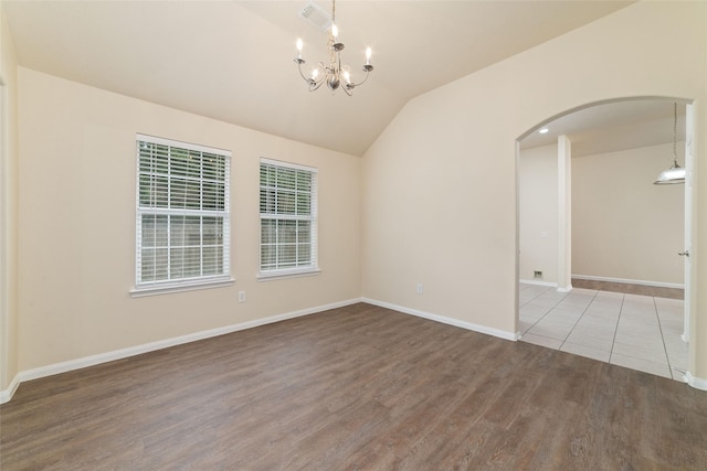 unfurnished room with arched walkways, a chandelier, baseboards, wood finished floors, and lofted ceiling