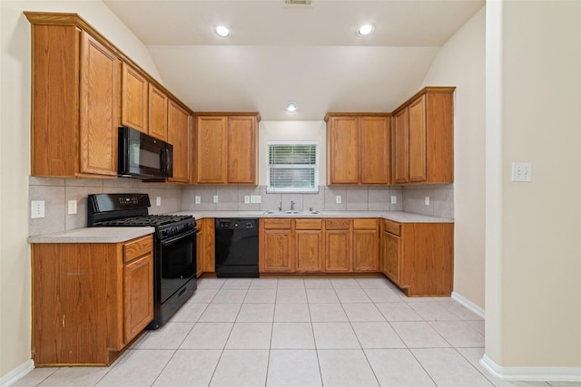 kitchen with decorative backsplash, brown cabinetry, a sink, light countertops, and black appliances