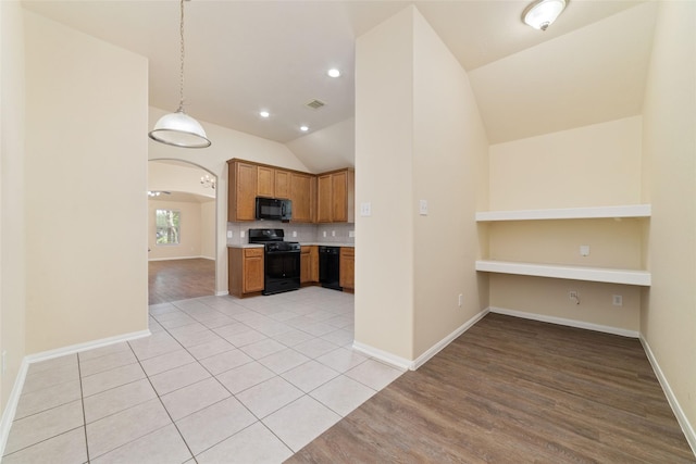kitchen with light countertops, baseboards, lofted ceiling, visible vents, and black appliances