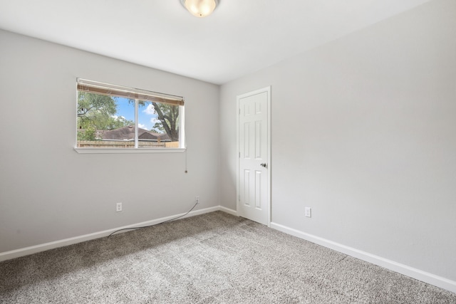 carpeted empty room featuring baseboards