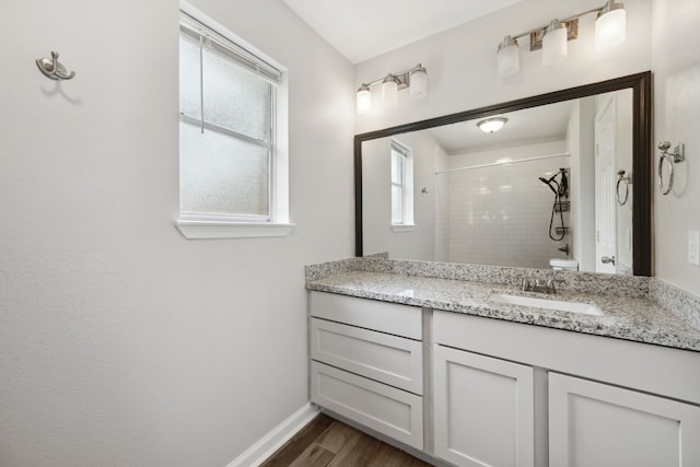 full bathroom featuring vanity, baseboards, wood finished floors, and a tile shower