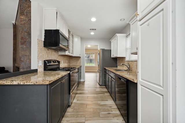 kitchen featuring light wood-style floors, white cabinets, a sink, backsplash, and stainless steel appliances
