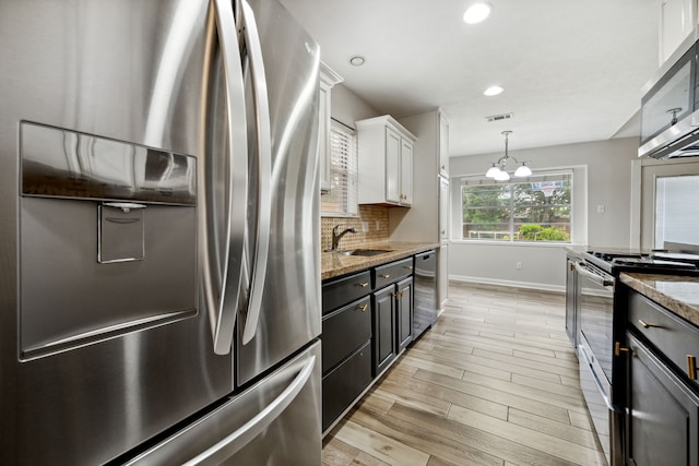kitchen with a sink, light wood-style flooring, stainless steel appliances, baseboards, and visible vents