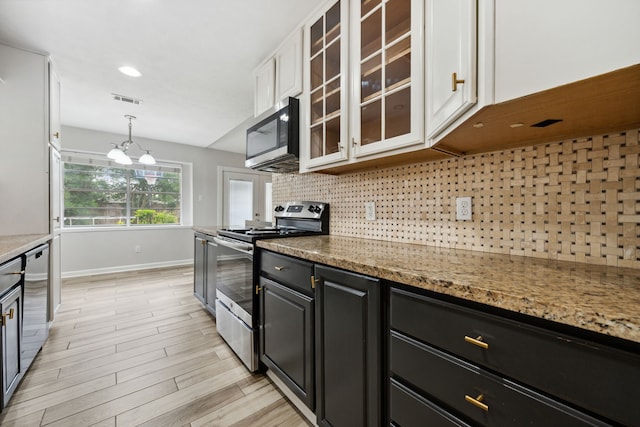 kitchen featuring appliances with stainless steel finishes, baseboards, decorative backsplash, visible vents, and glass insert cabinets