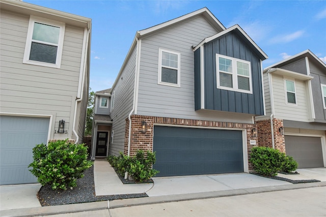 townhome / multi-family property with brick siding, an attached garage, board and batten siding, and concrete driveway
