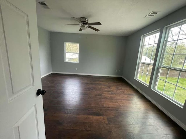 unfurnished room featuring baseboards, dark wood-style flooring, ceiling fan, and visible vents