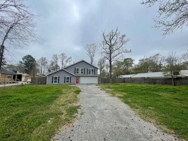 view of front of house with an attached garage, fence, a front yard, and gravel driveway