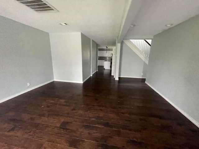 unfurnished living room with baseboards, stairs, wood finished floors, and visible vents