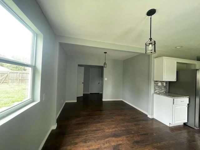 interior space with baseboards, freestanding refrigerator, dark wood-style flooring, and white cabinetry