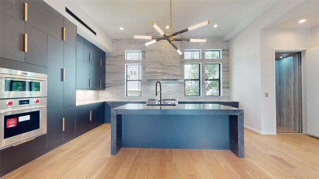 519 Memorial Heights Dr, Houston, TX 77007 - kitchen featuring light wood-type flooring, a sink, decorative backsplash, and a center island with sink