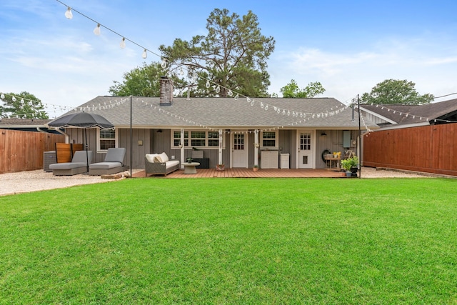 back of house with fence, a chimney, an outdoor living space, a shingled roof, and a lawn