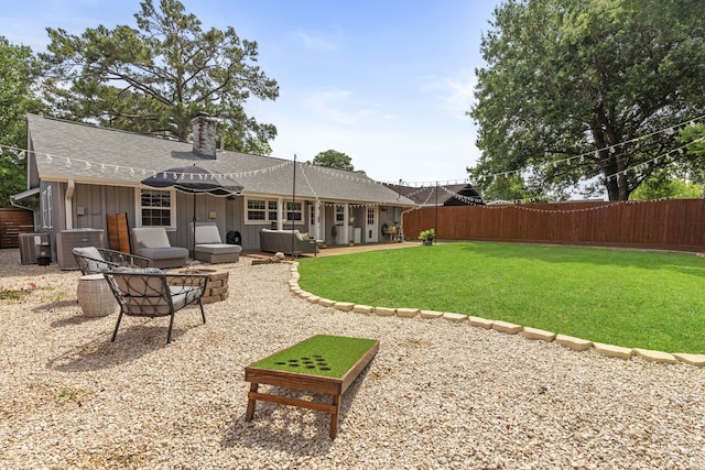 rear view of property featuring a fenced backyard, board and batten siding, a chimney, and a shingled roof