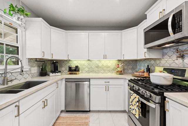 kitchen with a sink, light countertops, stainless steel appliances, and white cabinetry