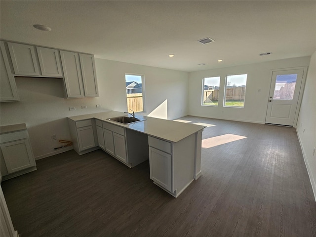 kitchen with visible vents, a sink, a peninsula, and dark wood-style floors
