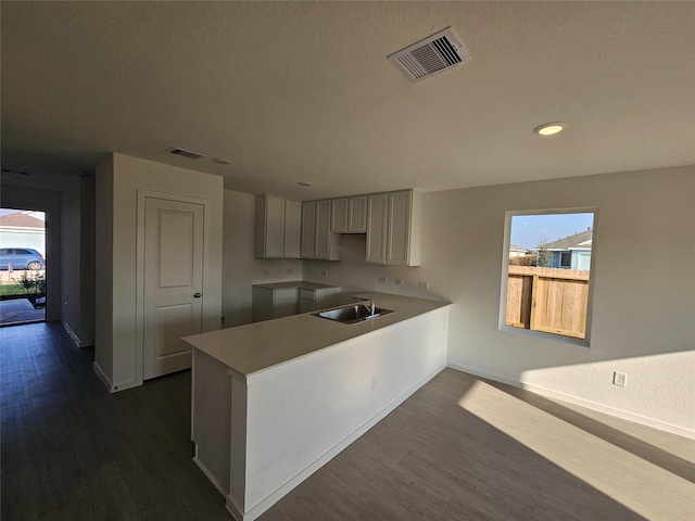 kitchen featuring a sink, baseboards, dark wood-style floors, and visible vents