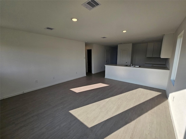 unfurnished living room with dark wood finished floors, baseboards, recessed lighting, and visible vents