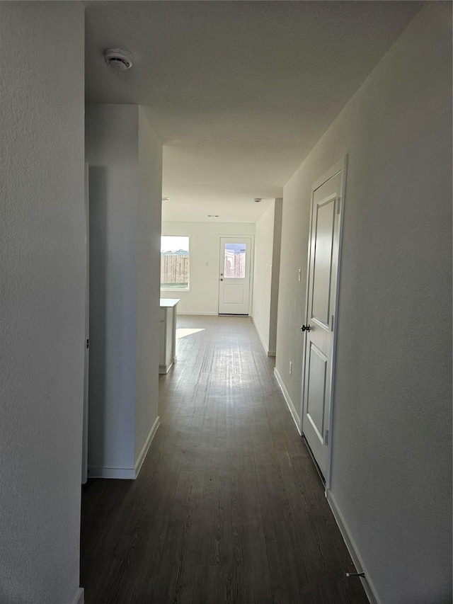 hall with dark wood-style flooring and baseboards