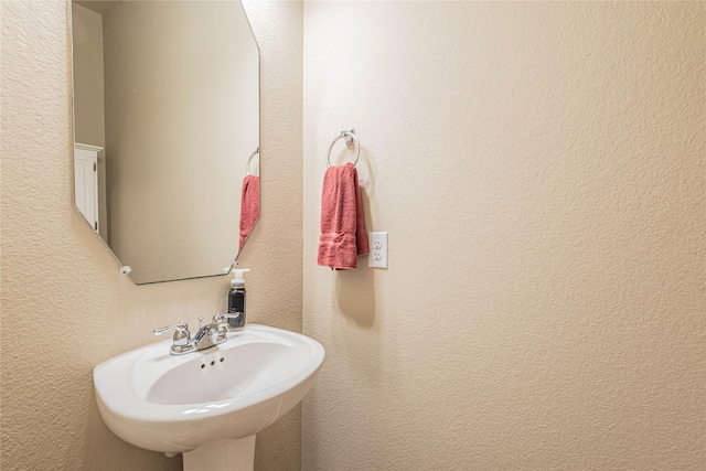 bathroom with a textured wall and a sink