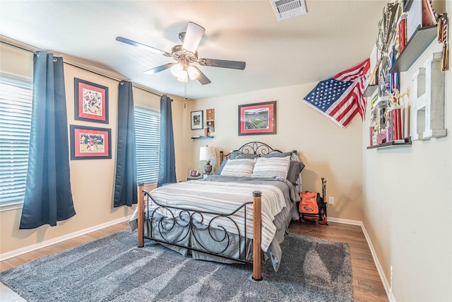bedroom featuring visible vents, baseboards, ceiling fan, and wood finished floors