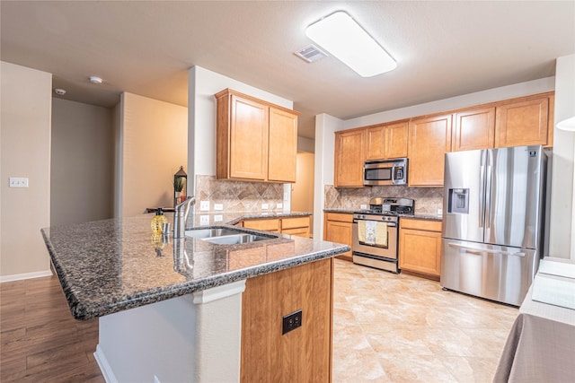 kitchen with visible vents, appliances with stainless steel finishes, tasteful backsplash, a sink, and a peninsula