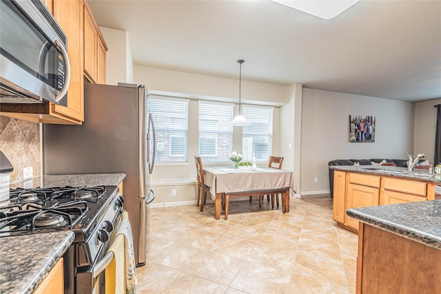 kitchen with decorative light fixtures, tasteful backsplash, a sink, stainless steel microwave, and gas range oven
