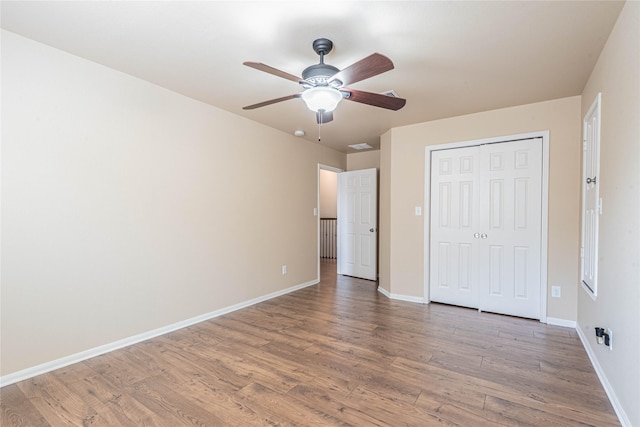unfurnished bedroom with baseboards, ceiling fan, a closet, and wood finished floors
