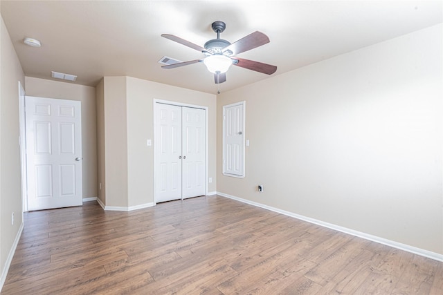 unfurnished bedroom with baseboards, visible vents, wood finished floors, and a closet