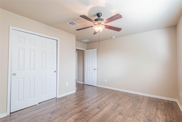 unfurnished bedroom featuring visible vents, baseboards, wood finished floors, and a closet