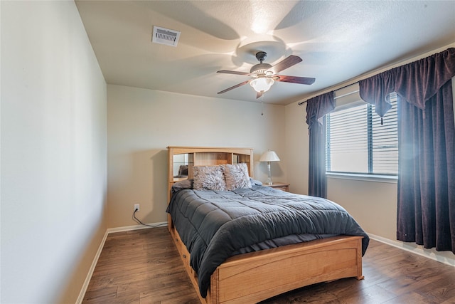 bedroom with ceiling fan, baseboards, visible vents, and wood finished floors