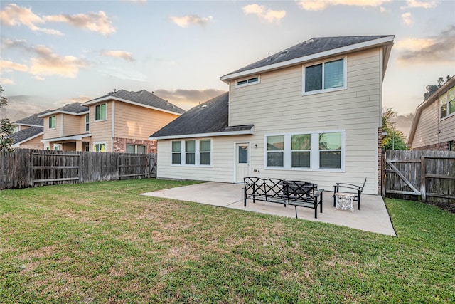 back of house at dusk with a yard, a fenced backyard, and a patio area