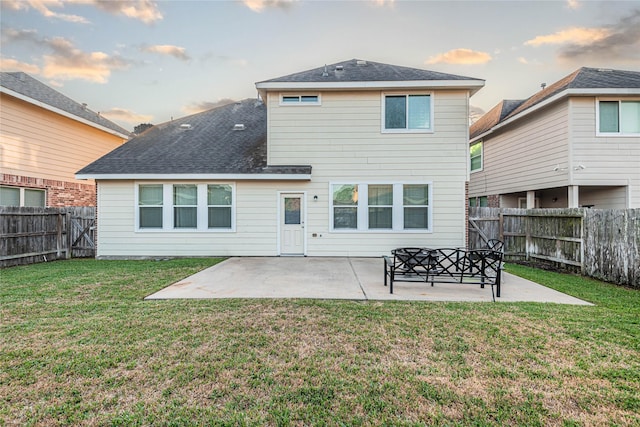 back of property at dusk with a patio, a fenced backyard, and a lawn