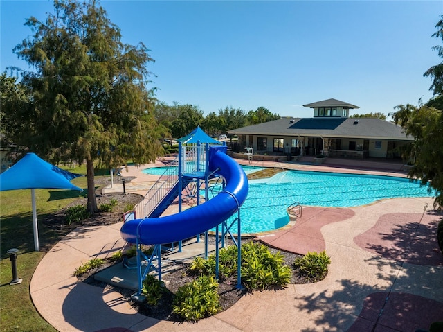 community pool with a water slide and a patio area