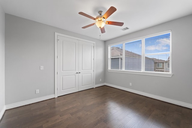 unfurnished bedroom featuring baseboards, visible vents, and dark wood finished floors