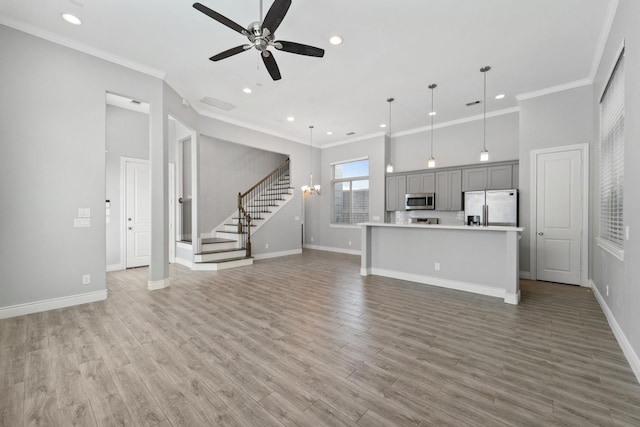 unfurnished living room with crown molding, ceiling fan, and stairway