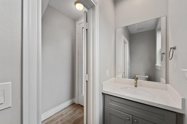 bathroom with vanity, baseboards, wood finished floors, and toilet