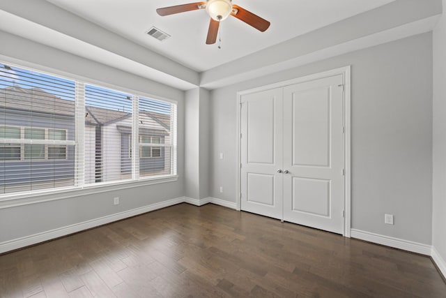 unfurnished bedroom with visible vents, a closet, baseboards, ceiling fan, and dark wood finished floors