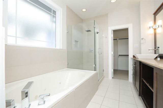 bathroom featuring vanity, a whirlpool tub, tile patterned floors, a spacious closet, and a shower stall