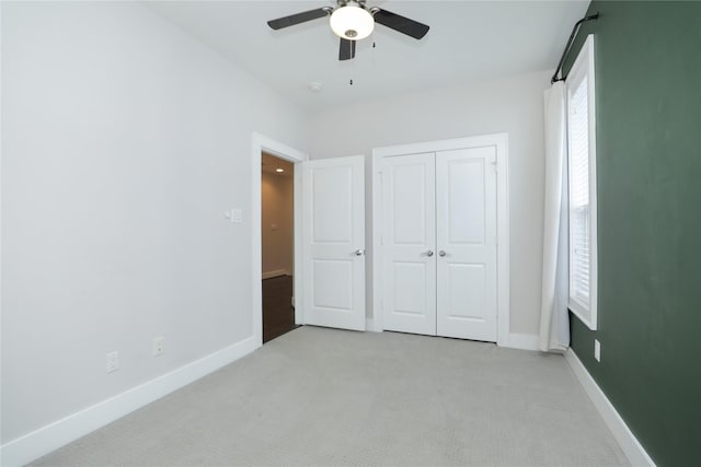 unfurnished bedroom featuring baseboards, ceiling fan, a closet, and light colored carpet