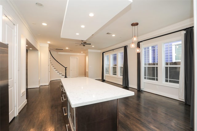 kitchen featuring dark wood-style flooring, dark brown cabinetry, ornamental molding, and a center island