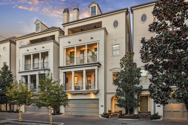 exterior space featuring a garage, driveway, a chimney, and stucco siding