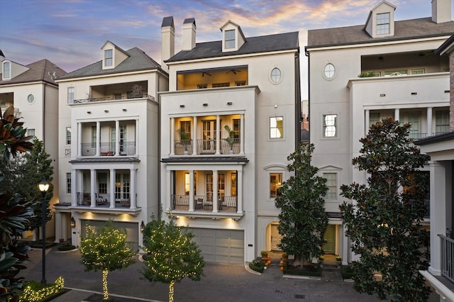 back of property featuring a garage, stucco siding, and a chimney