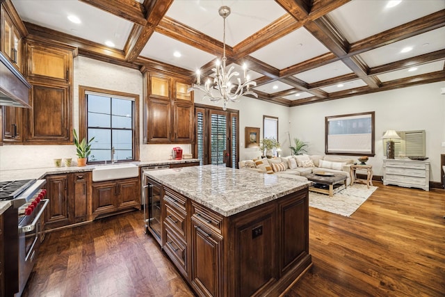kitchen with light stone counters, a sink, dark wood finished floors, range with two ovens, and open floor plan
