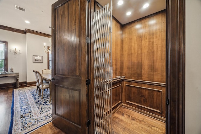 details featuring elevator, baseboards, wood finished floors, visible vents, and ornamental molding
