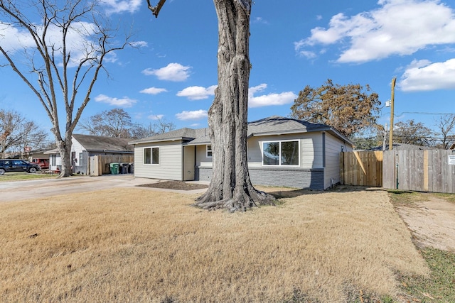view of front of home featuring fence, concrete driveway, a front lawn, and brick siding