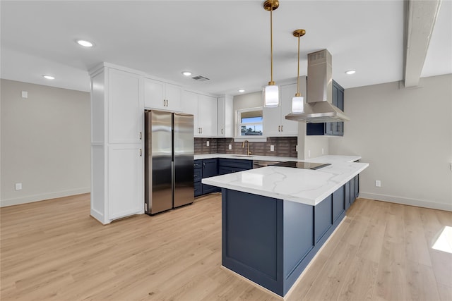 kitchen with freestanding refrigerator, a peninsula, range hood, black electric cooktop, and a sink