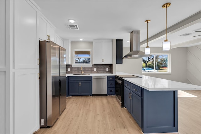 kitchen featuring visible vents, a peninsula, stainless steel appliances, island exhaust hood, and blue cabinetry
