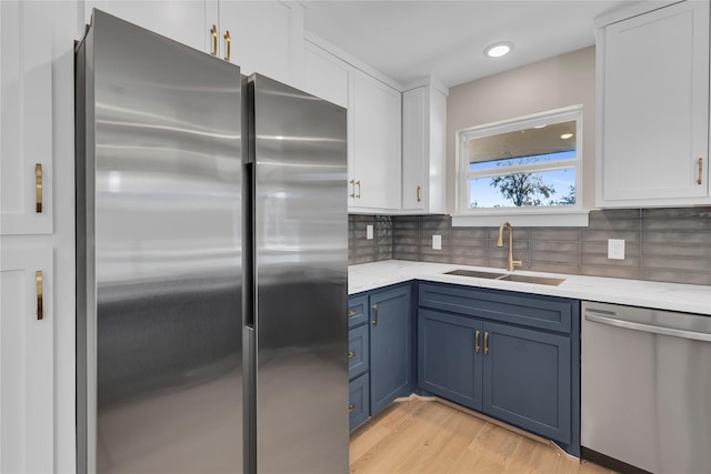 6014 W 43rd St, Houston, TX 77092 - kitchen with appliances with stainless steel finishes, blue cabinetry, white cabinetry, and tasteful backsplash