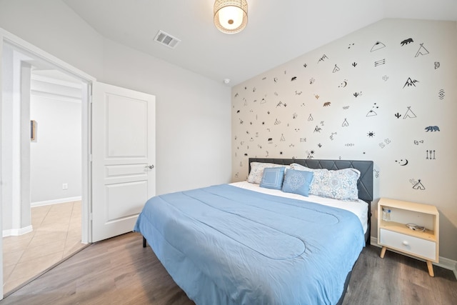 bedroom featuring baseboards, lofted ceiling, wood finished floors, and visible vents