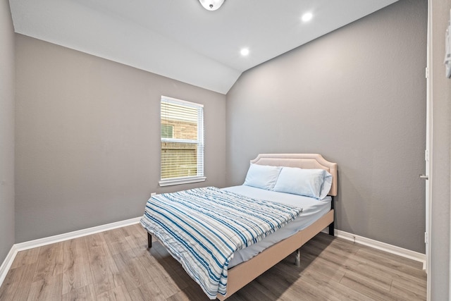 bedroom featuring baseboards, wood finished floors, and lofted ceiling