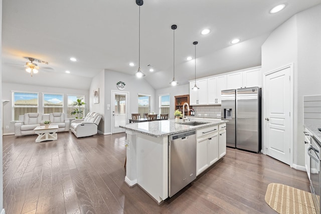 kitchen featuring a ceiling fan, a center island with sink, a sink, vaulted ceiling, and stainless steel appliances